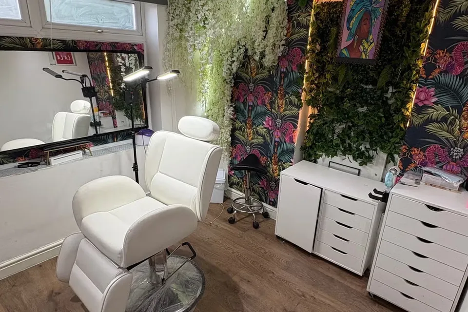 The hair room at the studio, with a styling chair, mirror and a floral feature wall