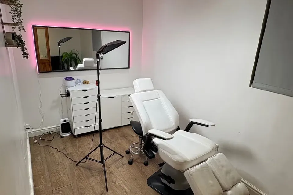 A private treatment room with a reclining bed, ring light and mirror