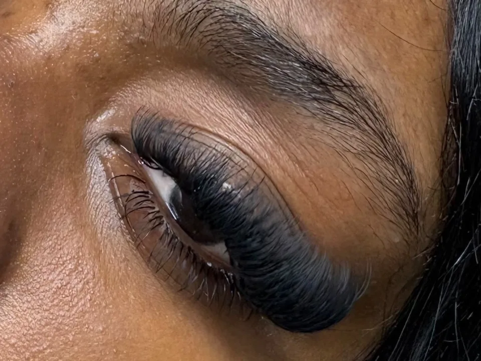 Close-up of dense black volume lash extensions on a closed eye beneath a groomed brow