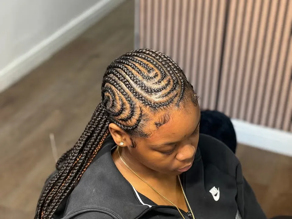 Curved cornrows braided close to the scalp in a patterned design